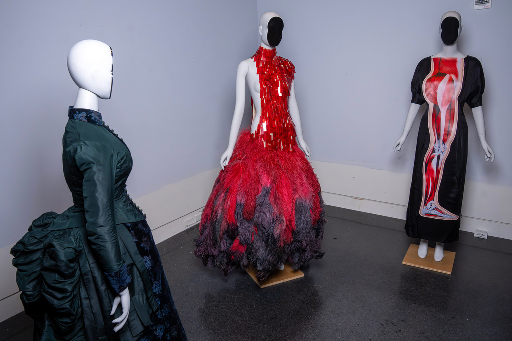 A vintage walking dress, from left, an Alexander McQueen dress, and a Christopher Kane dress are held in preparation for The Metropolitan Museum of Art's spring exhibition, "Costume Art," on Thursday, Feb. 12, 2026, in New York. (Photo by Charles Sykes/Invision/AP)