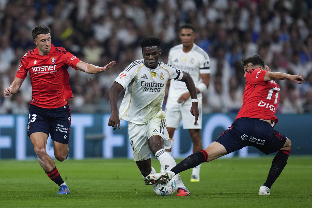 Real Madrid's Aurelien Tchouameni in action between Osasuna's Abel Bretones, left, and Ante Budimir during the La Liga soccer match between Real Madrid and Osasuna in Madrid, Spain, Tuesday, Aug. 19, 2025. (AP Photo/Manu Fernandez)
