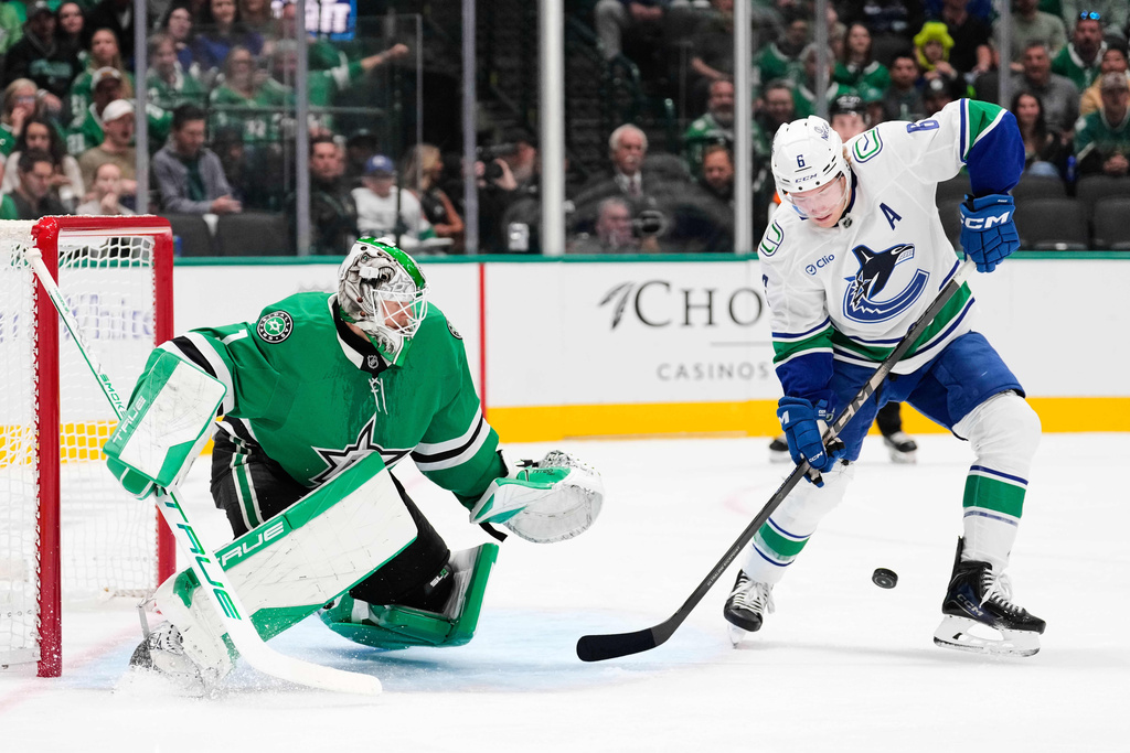 Vancouver Canucks right wing Brock Boeser (6) attempts to control a shot against Dallas Stars goaltender Casey Desmith in the second period of an NHL hockey game Thursday, Oct. 16, 2025, in Dallas. (AP Photo/Tony Gutierrez)