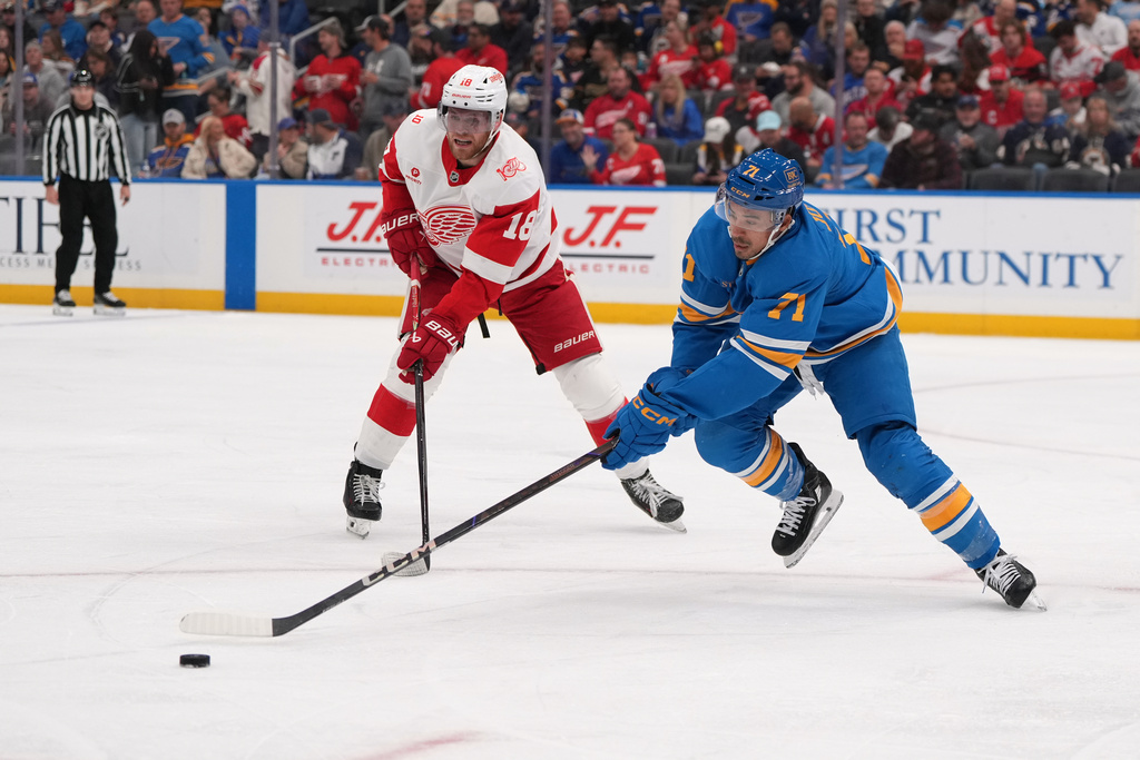 St. Louis Blues' Mathieu Joseph (71) reaches for a loose puck as Detroit Red Wings' Andrew Copp (18) watches during the second period of an NHL hockey game Tuesday, Oct. 28, 2025, in St. Louis. (AP Photo/Jeff Roberson)