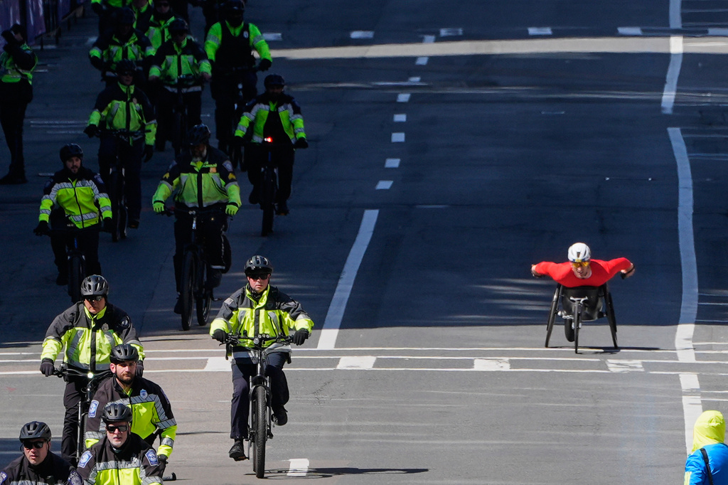 Jetze Plat, of the Netherlands, right, passes police cyclists while approaching the finish line of the Boston Marathon, Monday, April 20, 2026, in Boston. (AP Photo/Charles Krupa)