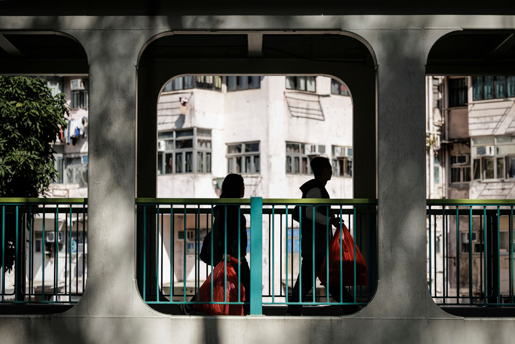 Two people carry red bags with offerings as they walk along a bridge in Hong Kong, Feb. 11, 2026. (AP Photo/May James)
