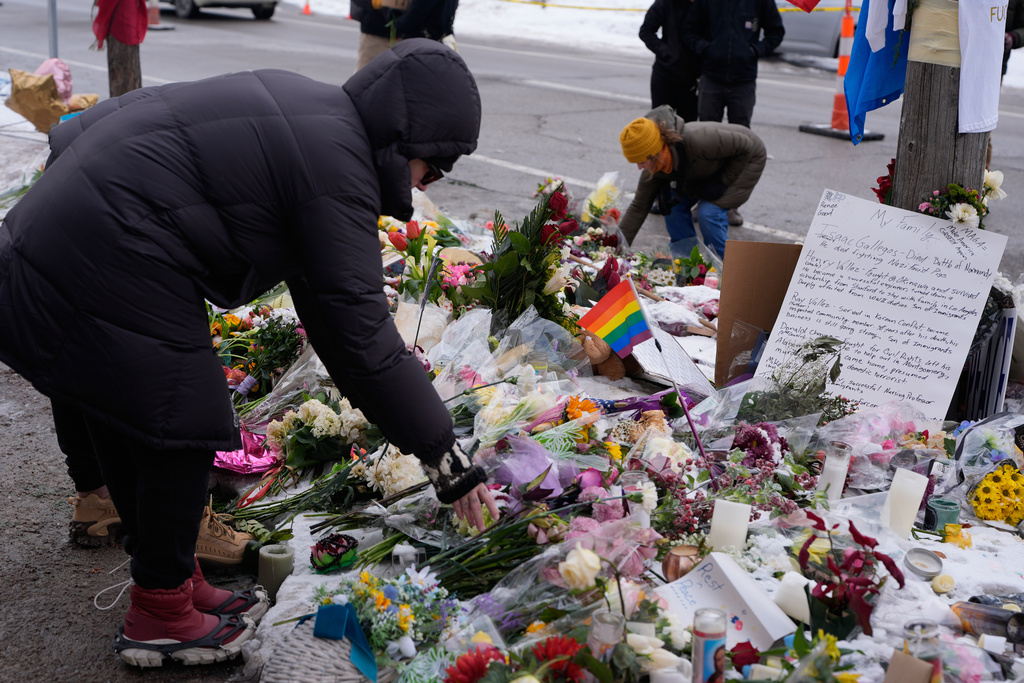 People place flowers for a memorial at the site where Renee Good was fatally shot by an ICE agent in Minneapolis, Saturday, Jan. 10, 2026. (AP Photo/Jen Golbeck)