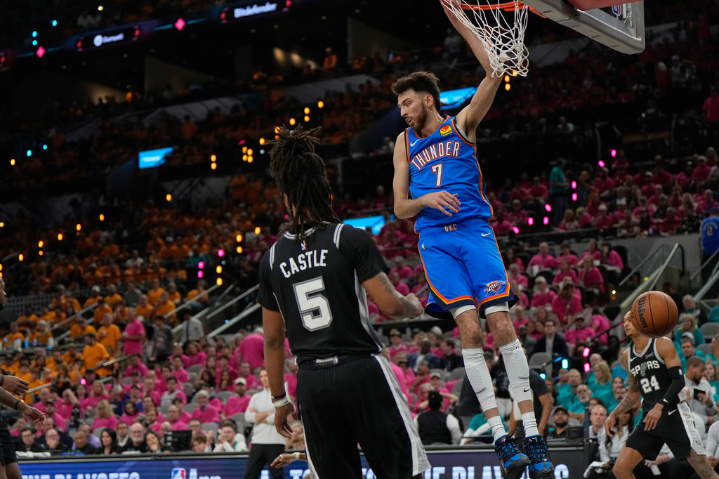 Oklahoma City Thunder center Chet Holmgren (7) hangs on the rim next to San Antonio Spurs guard Stephon Castle (5) after a dunk during the second half of Game 3 in the Western Conference finals NBA basketball playoffs series Friday, May 22, 2026, in San Antonio. (AP Photo/Ashley Landis)