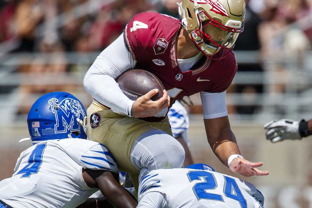 Florida State quarterback DJ Uiagalelei (4) tries to jump over Memphis defensive backs An'Darius Coffey (4) and Greg Rubin (24) during the first half of an NCAA college football game, Saturday, Sept. 14, 2024, in Tallahassee, Fla. (AP Photo/Colin Hackley)