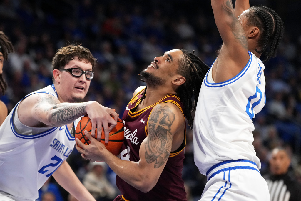 Loyola Chicago's Kayde Dotson, center, heads to the basket as Saint Louis' Robbie Avila, left, and Kellen Thames, right, defend during the first half of an NCAA college basketball game Wednesday, March 4, 2026, in St. Louis. (AP Photo/Jeff Roberson)