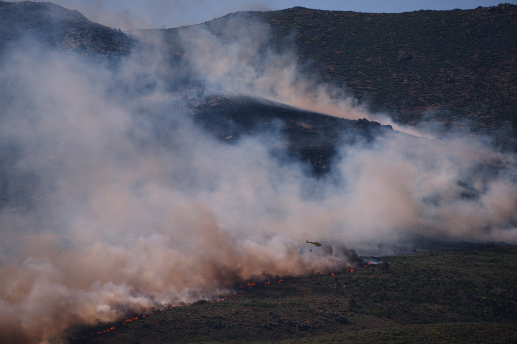 A firefighting helicopter drops water on the flames as a wildfire advances near Burgohondo, Ávila province, Spain, Friday, July 24, 2026. (AP Photo/Manu Fernandez)
