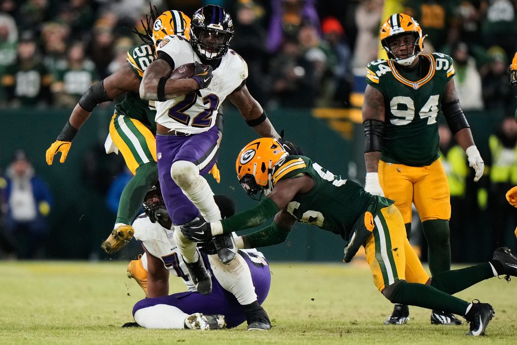 Baltimore Ravens running back Derrick Henry (22) runs the ball past Green Bay Packers linebacker Edgerrin Cooper (56) and defensive end Rashan Gary (52) during the second half of an NFL football game, Saturday, Dec. 27, 2025, in Green Bay, Wis. (AP Photo/Morry Gash)