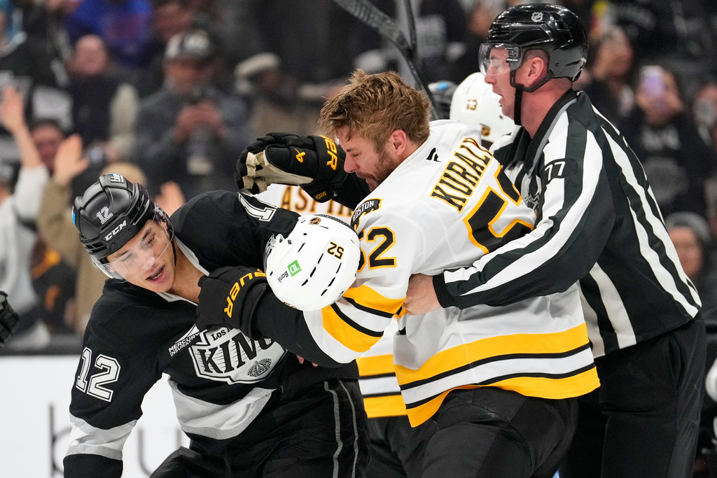 Los Angeles Kings left wing Trevor Moore, left, and Boston Bruins center Sean Kuraly, center, scuffle during the second period of an NHL hockey game Friday, Nov. 21, 2025, in Los Angeles. (AP Photo/Mark J. Terrill)