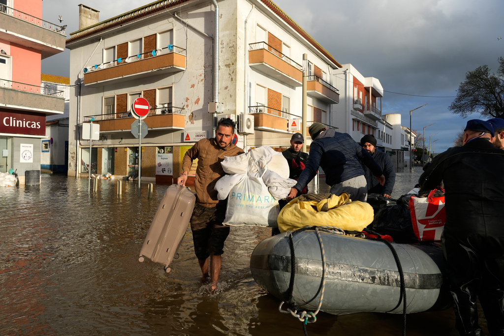 Residents of a hotel are evacuated by police officers and marines by inflatable boat along a flooded street after the Sado River overflowed following heavy rains in Alcácer do Sal, southern Portugal, Friday, Feb. 6, 2026. (AP Photo/Ana Brigida)