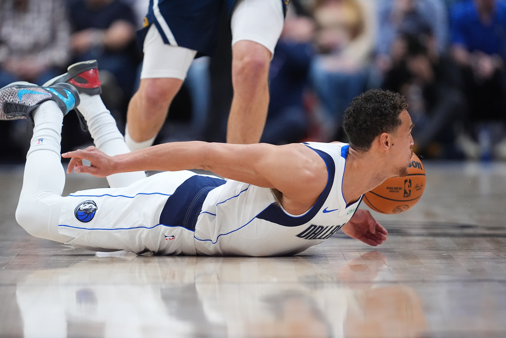 Dallas Mavericks forward Dwight Powell dives after a loose ball in the first half of an NBA basketball game against the Denver Nuggets Wednesday, March 25, 2026, in Denver. (AP Photo/David Zalubowski)