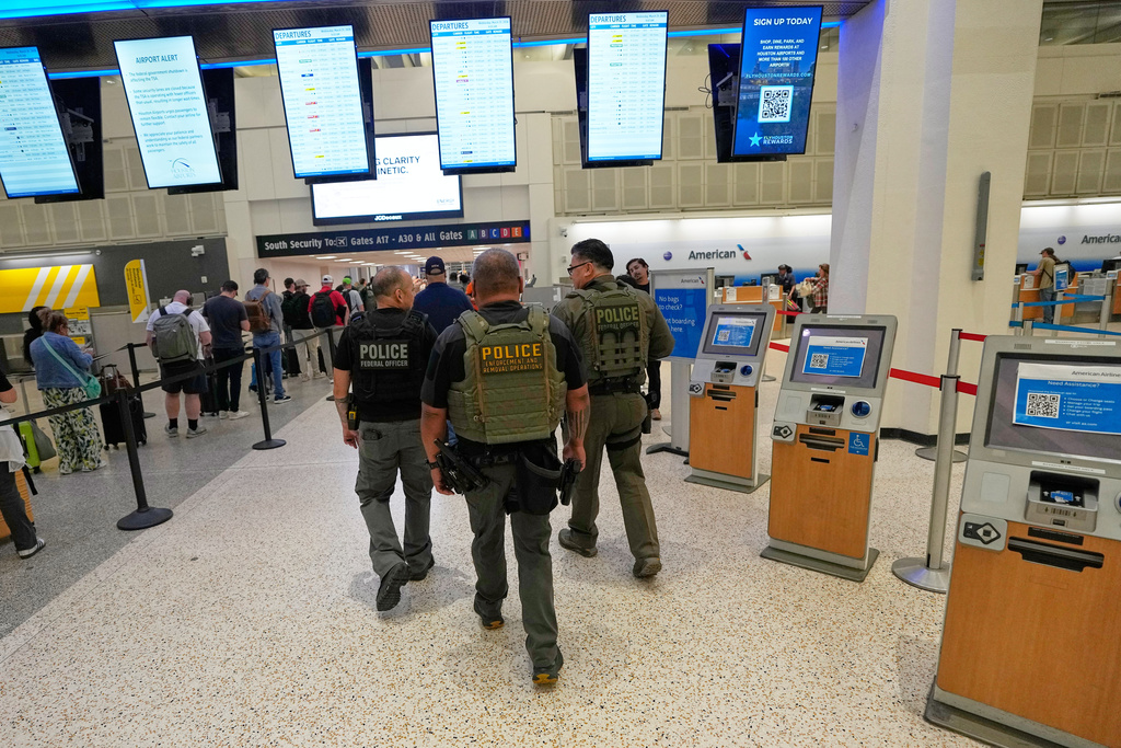 Federal immigration officers walk toward a security checkpoint at George Bush Intercontinental Airport, Wednesday, March 25, 2026, in Houston. (AP Photo/David J. Phillip)
