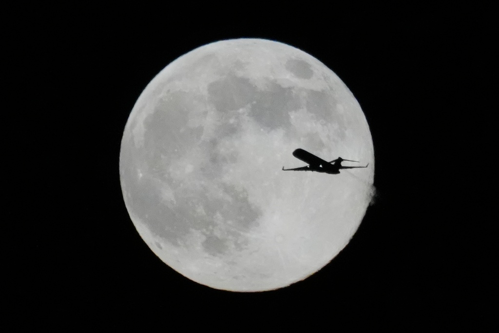 A plane flies past the full moon as the supermoon rises up Thursday, Dec. 4, 2025, in Chicago. (AP Photo/Kiichiro Sato)