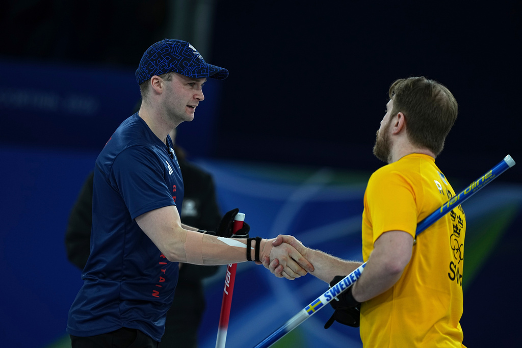 Britain's Bruce Mouat shakes hands with Sweden's Rasmus Wranaa following their semi-finals round of the mixed doubles curling match, at the 2026 Winter Olympics, in Cortina d'Ampezzo, Italy, Monday, Feb. 9, 2026. (AP Photo/Fatima Shbair)