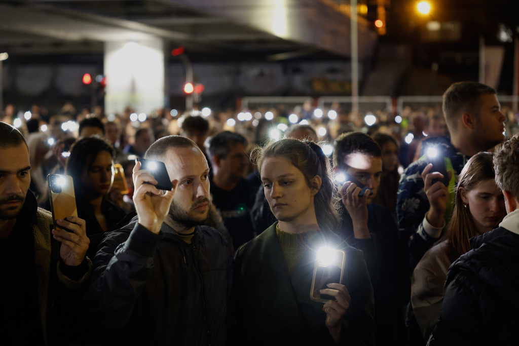 People use the lights on their cell phones as they observe sixteen minutes of silence during a protest eleven months after the deadly train station tragedy that sparked mass demonstrations against corruption in Belgrade, Serbia, Wednesday, Oct. 1, 2025. (AP Photo/Marko Drobnjakovic)