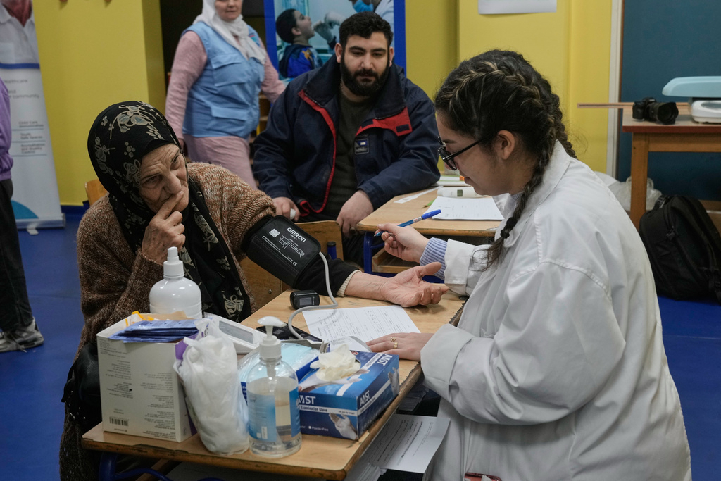 A nurse, right, measures the blood pressure of a woman who fled Israeli airstrikes in Dahiyeh, Beirut's southern suburbs, at a school turned into a shelter in Beirut, Lebanon, Saturday, March 7, 2026. (AP Photo/Bilal Hussein)