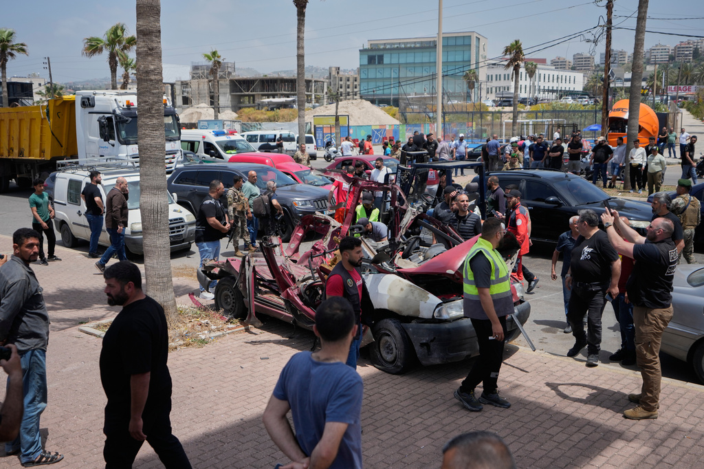 Security forces and emergency responders gather around a heavily damaged vehicle after it was hit in an Israeli airstrike in Sidon, Lebanon, Wednesday, May 13, 2026. (AP Photo/Mohammad Zaatari)