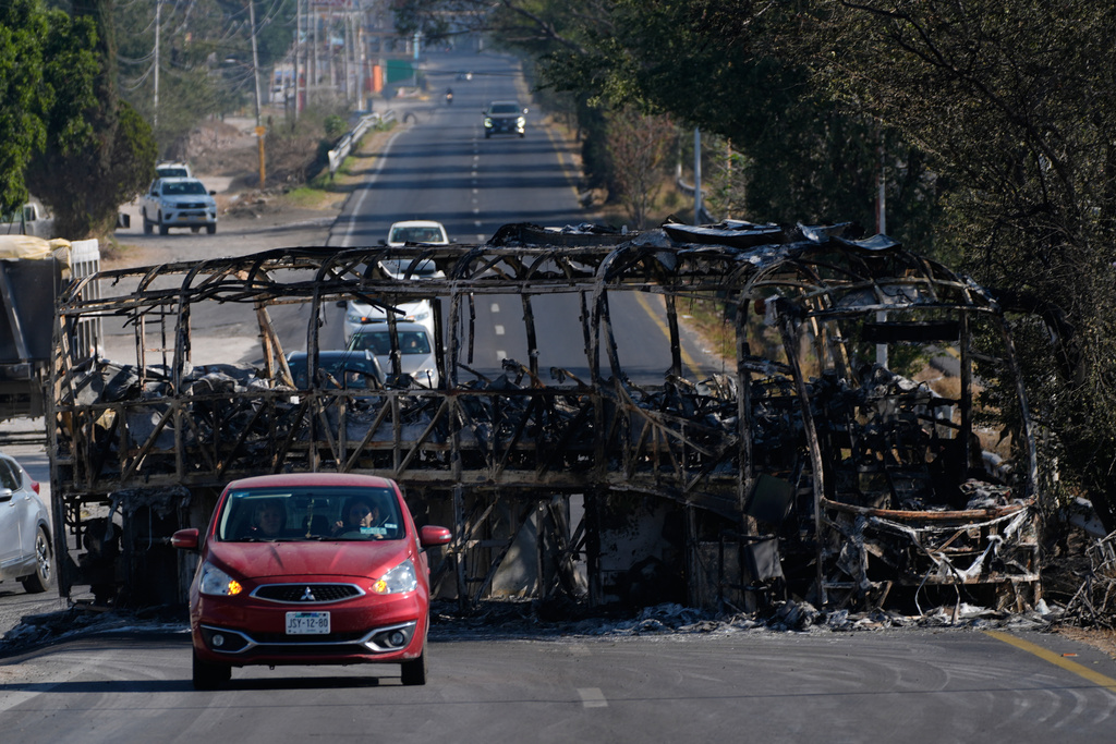 Vehicles drive past a charred bus the day after the Mexican army killed Jalisco New Generation Cartel leader Nemesio Oseguera Cervantes, known as "El Mencho," in Guadalajara, Mexico, Monday, Feb. 23, 2026. (AP Photo/Marco Ugarte)