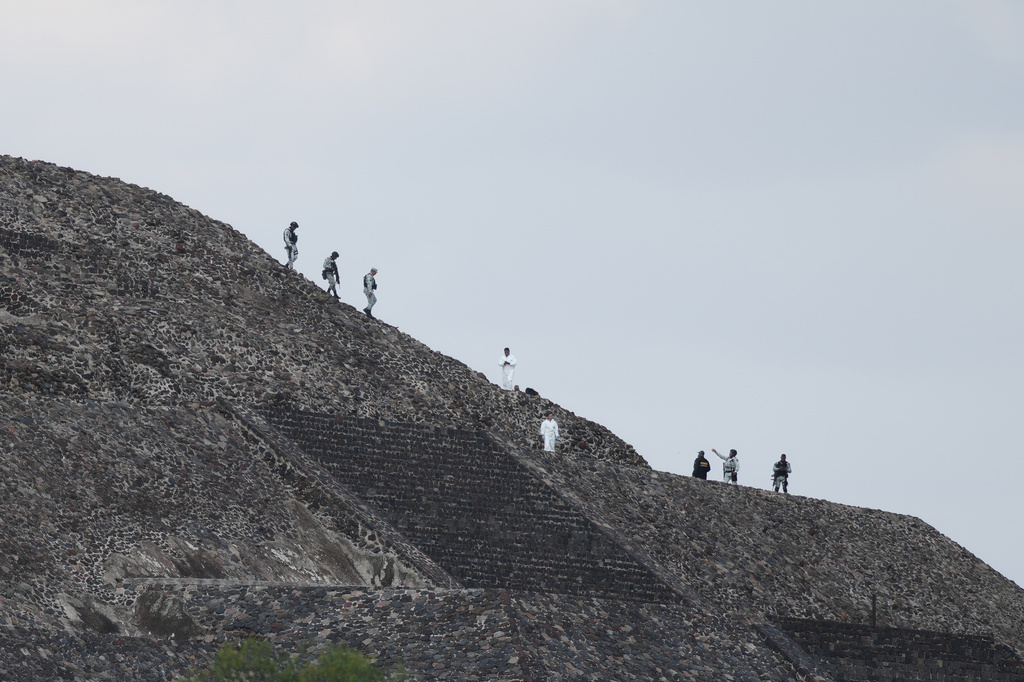 Police and forensic workers stand on a pyramid after authorities said a gunman opened fire in Teotihuacan, Mexico, Monday, April 20, 2026. (AP Photo/Eduardo Verdugo)