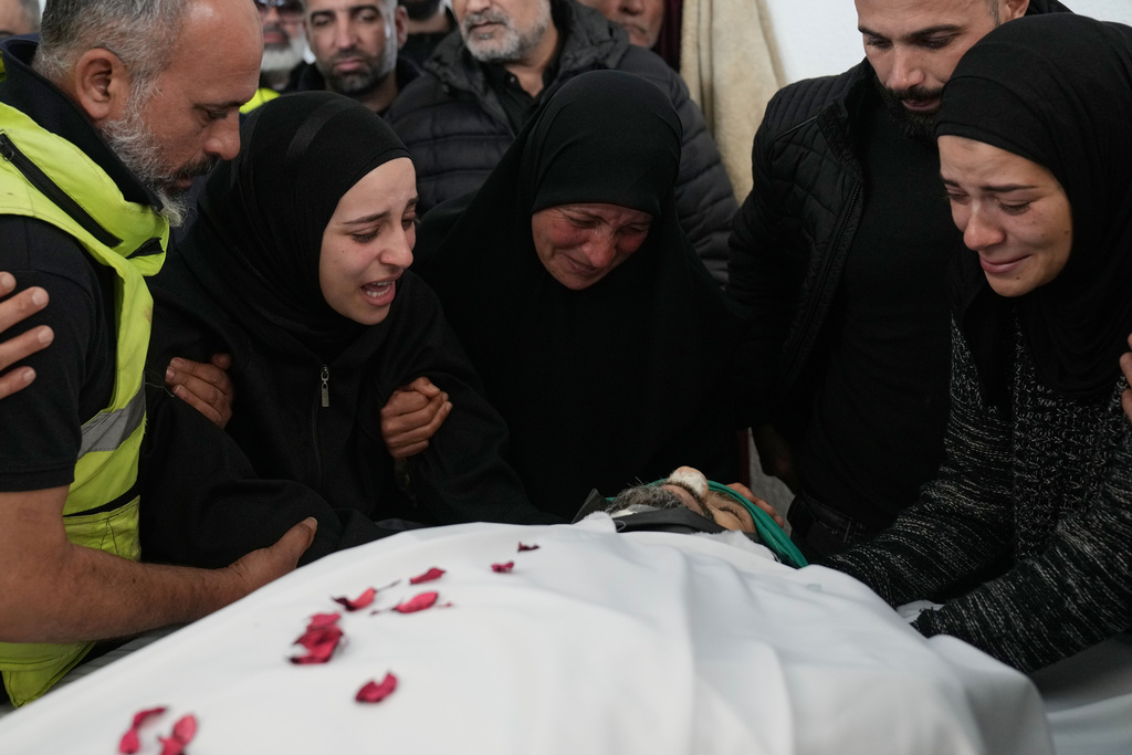 Family members of a paramedic who was killed in an Israeli airstrike, mourn over his body at a morgue, in Tyre, south Lebanon, Wednesday, March 25, 2026. (AP Photo/Hussein Malla)