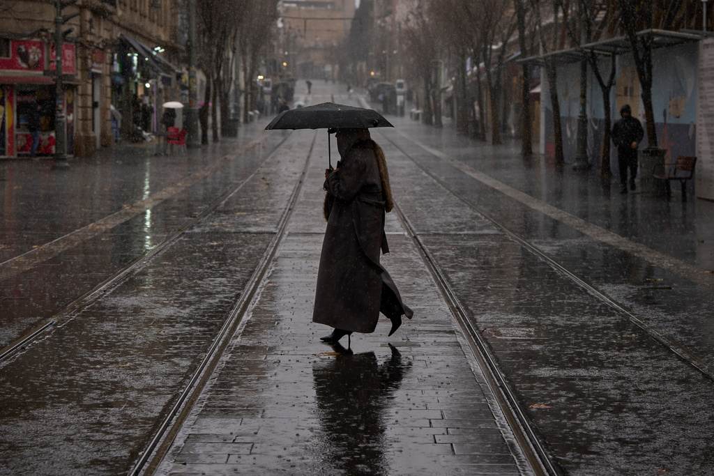 A woman walks in downtown Jerusalem during rainfall, Tuesday, Jan. 13, 2026. (AP Photo/Ohad Zwigenberg)