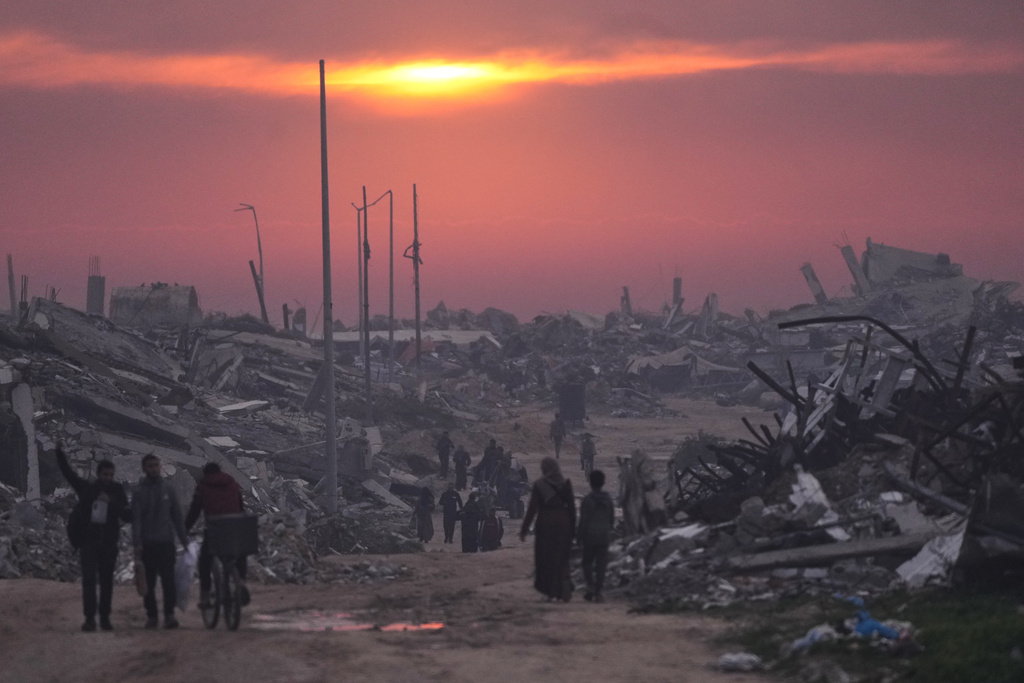 Palestinians walk through the ruins of destroyed buildings as the sun sets over Gaza City, Sunday, Jan. 4, 2026. (AP Photo/Jehad Alshrafi)