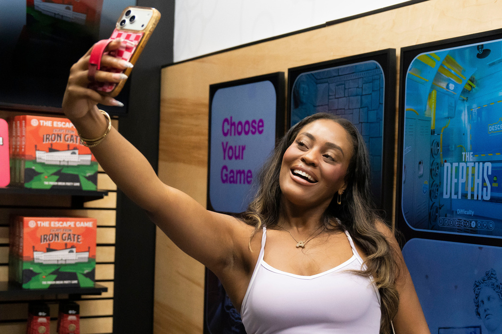 Phoenix-based content creator Aiesha Beasley films herself at The Escape Game in Gilbert, Ariz., Thursday, Aug. 13, 2026. (AP Photo/Rebecca Noble)