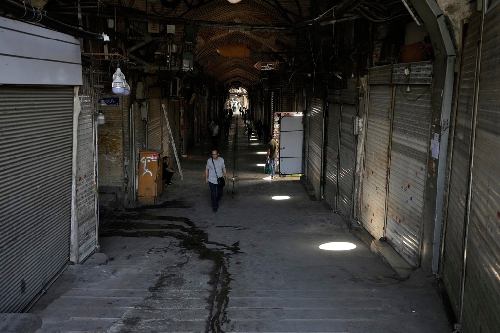 FILE.- Few pedestrians walk along the historic Grand Bazaar as most shops remain shuttered, in Tehran, Iran, Monday, June 16, 2025. (AP Photo/Vahid Salemi, File