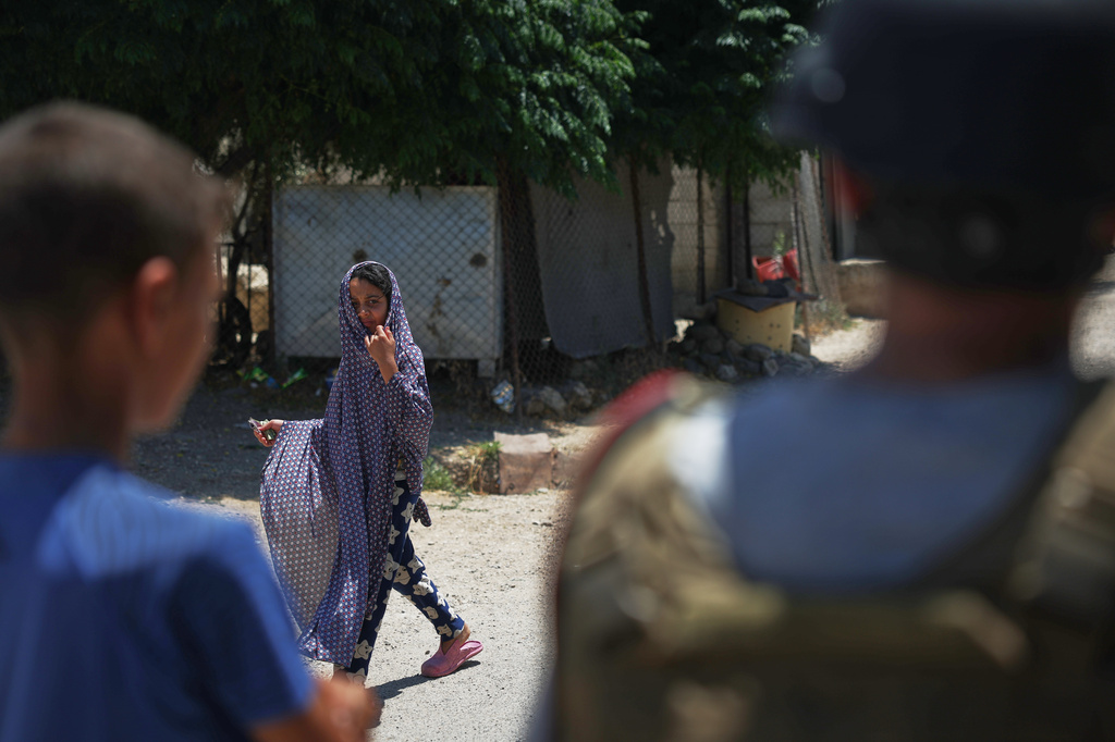 A girl walks through the village of Abdin, Daraa province, Syria, Monday, June 29, 2026, as other residents look on.(AP Photo/Ghaith Alsayed)