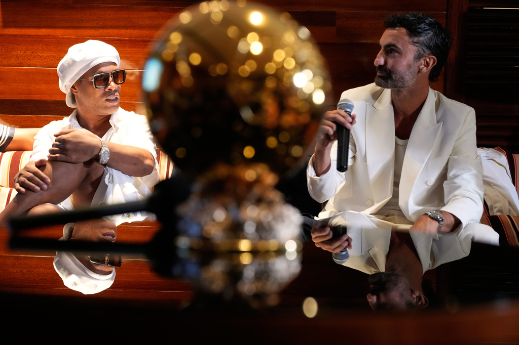 Brazilian football legend Ronaldinho, left, listens as Giorgio Mallone, Ravenna FC creative director, talks about the team's new kit during a media event celebrating Ronaldinho's recent signing with the Italian soccer club, at Cipriani Downtown Miami restaurant, Tuesday, June 23, 2026, in Miami. (AP Photo/Rebecca Blackwell)