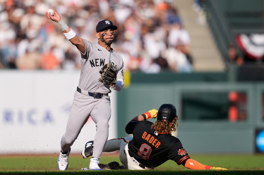 New York Yankees shortstop José Caballero, left, throws to first base after forcing San Francisco Giants' Harrison Bader (9) out at second base on a double play hit into by Patrick Bailey during the fourth inning of a baseball game in San Francisco, Saturday, March 28, 2026. (AP Photo/Jeff Chiu)