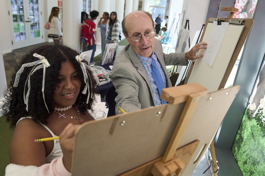 John Hutton, illustrator and a professor of art history at Salem College, helps Trinity Vanegas, 18, of Woodbridge, Va., to draw a portrait of President George Washington, Tuesday, Aug. 12, 2025, from his book, "How To Draw The Presidents and First Ladies," at The People's House, a museum in Washington. (AP Photo/Jacquelyn Martin)