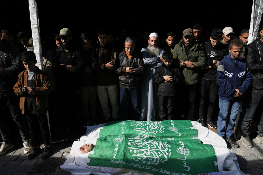 Palestinians pray during the funeral of Hamas' Al-Qassam Brigades operatives, whose bodies are draped in the group's flag, killed in an Israeli strike Saturday, in Gaza City, Sunday, Dec. 14, 2025. (AP Photo/Jehad Alshrafi)