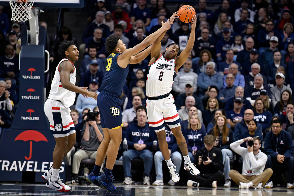 UConn guard Silas Demary Jr., right, grabs a rebound against Marquette forward Caedin Hamilton, center, as UConn forward Tarris Reed Jr., left, watches in the first half of an NCAA college basketball game, Sunday, Jan. 4, 2026, in Storrs, Conn. (AP Photo/Jessica Hill)