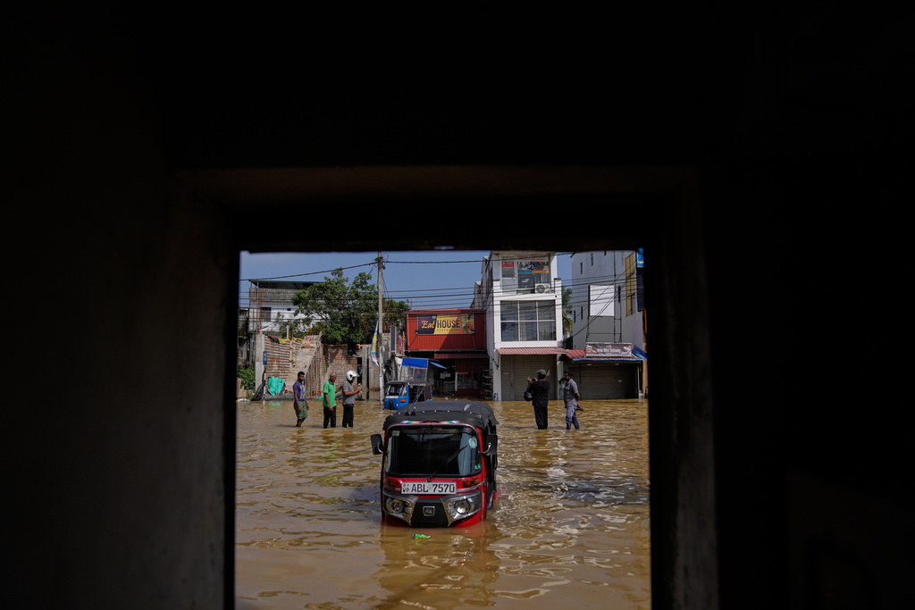 People wade through a submerged area of Colombo, Sri Lanka, following flooding on Sunday, Nov. 30, 2025. (AP Photo/Eranga Jayawardena)