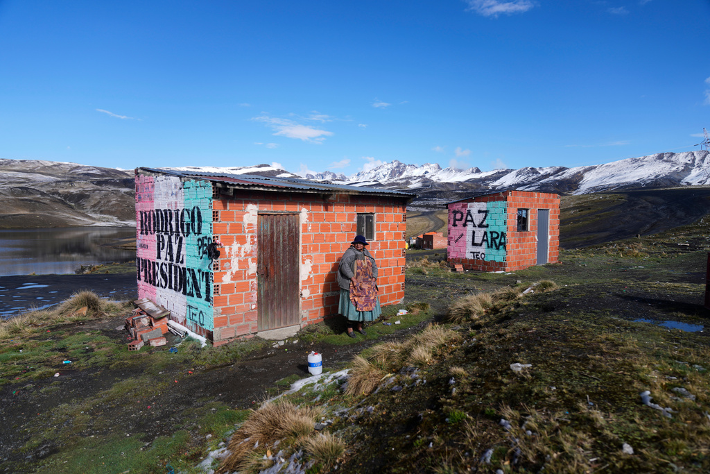 A woman stands next to a mural promoting presidential candidate Rodrigo Paz on La Cumbre ahead of the presidential runoff election, on the outskirts of La Paz, Bolivia, Saturday, Oct. 18, 2025. (AP Photo/Juan Karita)