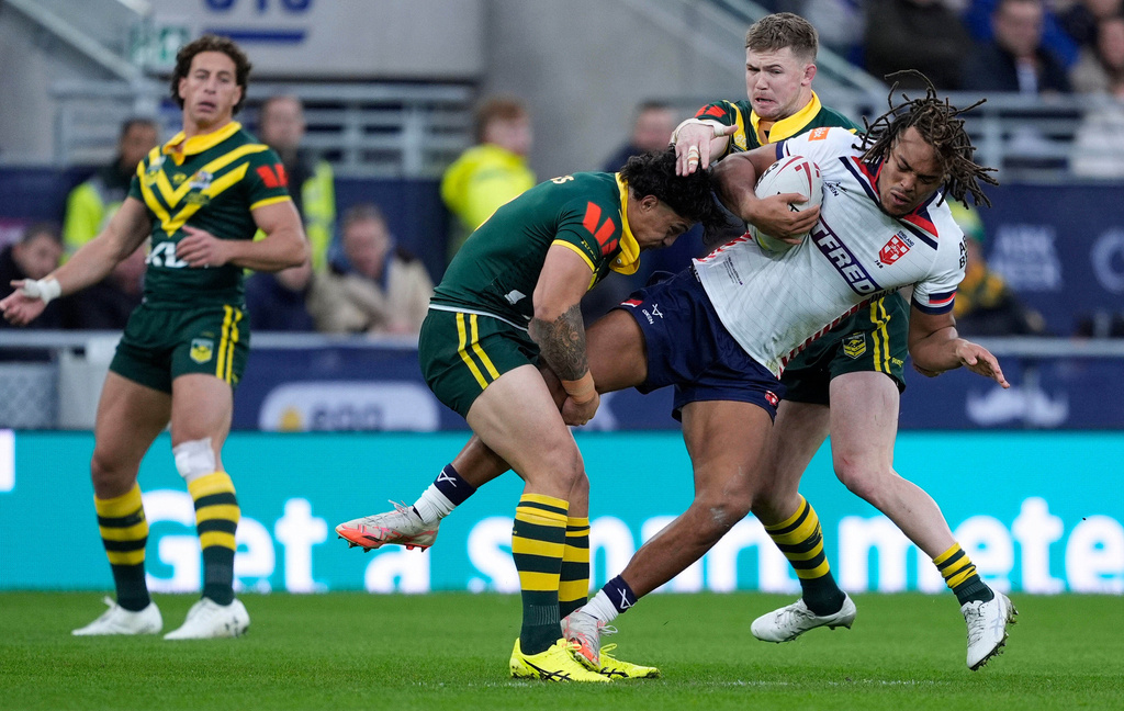 England's Dom Young, right, is tackled by Australia's Kotoni Staggs, left, and Hudson Young during their Ashes Series rugby league match at the Hill Dickinson Stadium, Liverpool, England, Saturday, Nov. 1, 2025. (Peter Byrne/PA via AP)
