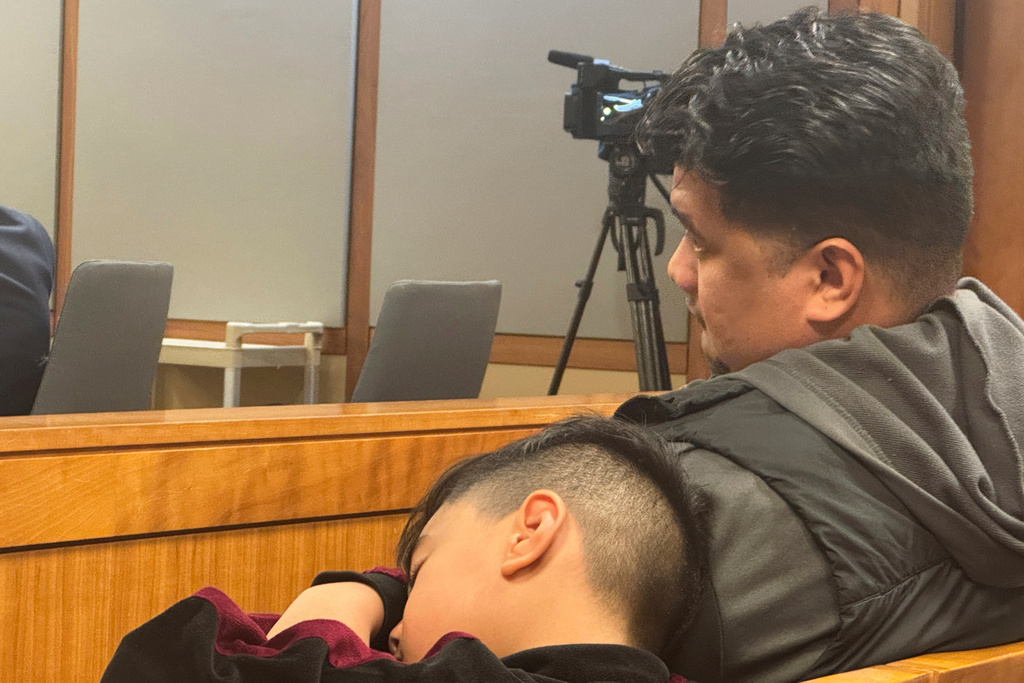 Michael Pese, one of the 10 American Samoa natives charged by the state of Alaska for voting irregularities, waits for his arraignment in a courtroom Thursday, Sept. 4, 2025, in Anchorage, Alaska, while his son Maximus naps. (AP Photo/Mark Thiessen)