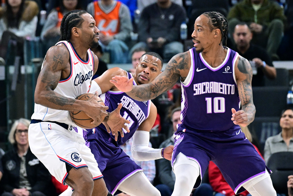 Sacramento Kings guard Russell Westbrook, center, and forward Demar Derozan (10) try to steal the ball from Los Angeles Clippers forward Kawhi Leonard, left, in the first half of an NBA basketball game Tuesday, Dec. 30, 2025, in Inglewood, Calif. (AP Photo/Wally Skalij)