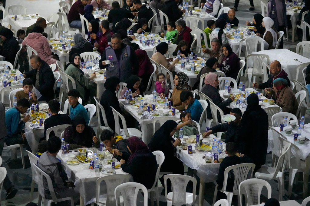 Displaced people who fled Israeli strikes from south Lebanon, gather for iftar, the Ramadan fast-breaking meal, at a school playground turned into a shelter, in the southern port city of Sidon, Lebanon, Monday, March 16, 2026. (AP Photo/Mohammed Zaatari)
