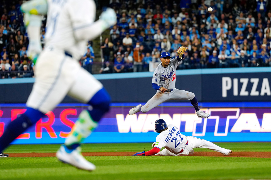 Los Angeles Dodgers shortstop Mookie Betts (50) puts out Toronto Blue Jays' Vladimir Guerrero Jr. (27) at second base as he throws to first to get out Bo Bichette, front left, for a third inning-ending double play during Game 1 of baseball's World Series in Toronto, Friday, Oct. 24, 2025. (Frank Gunn/The Canadian Press via AP)