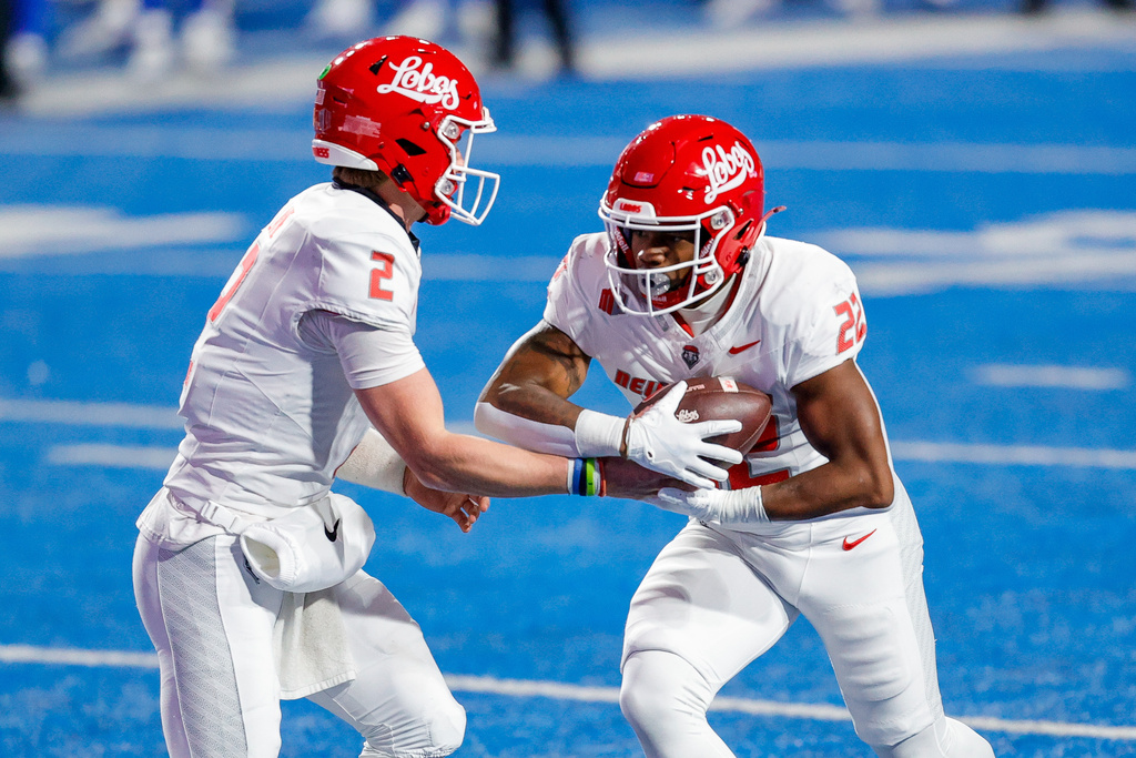 New Mexico running back Scottre Humphrey (22) receives the ball on a handoff from quarterback Jack Layne (2) against Boise State in the first half of an NCAA college football game, Saturday, Oct. 11, 2025, in Boise, Idaho. (AP Photo/Steve Conner)