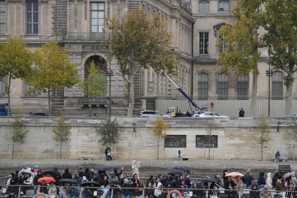 Police officers, background, look for clues by a basket lift used by thieves Sunday, Oct. 19, 2025 at the Louvre museum in Paris. (AP Photo/Thibault Camus)