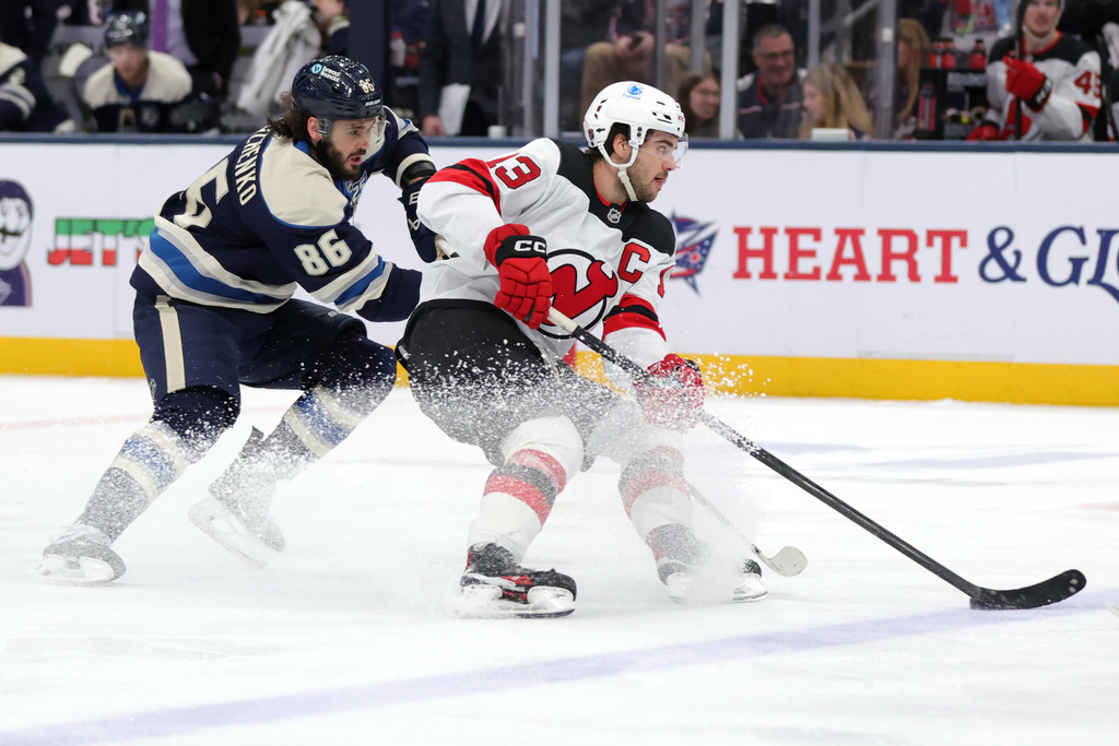 New Jersey Devils forward Nico Hischier, right, controls the puck in front of Columbus Blue Jackets forward Kirill Marchenko during the second period of an NHL hockey game in Columbus, Ohio, Wednesday, Dec. 31, 2025. (AP Photo/Paul Vernon)