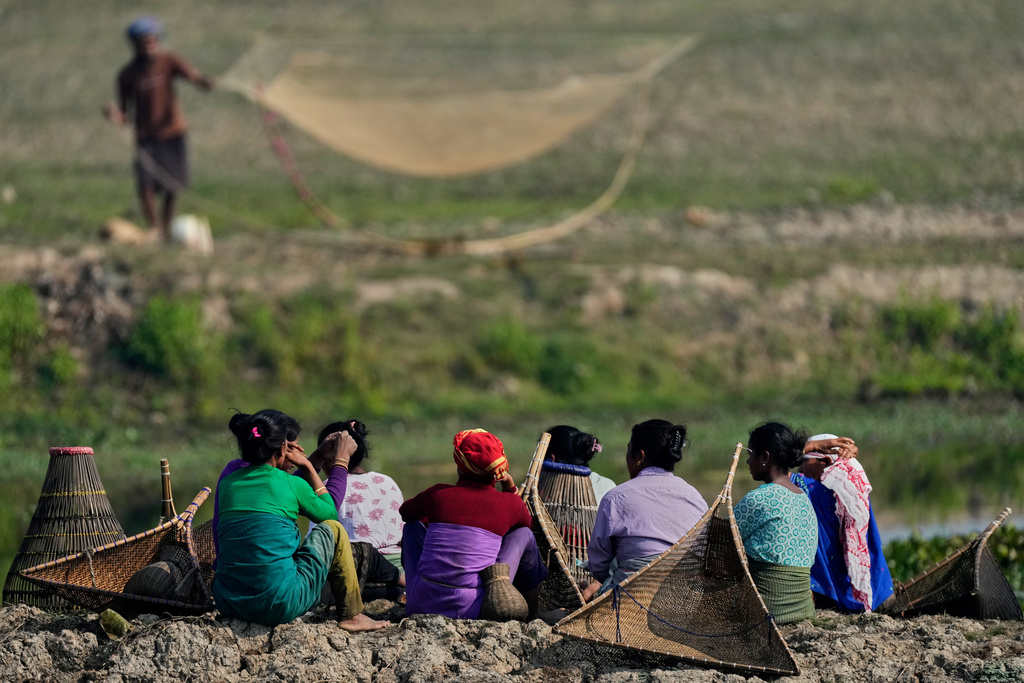 Tribal women with their fishing tools wait to participate in a community fishing as part of Bhogali Bihu celebrations which mark the end of the harvest season at Jalikhora village east of Guwahati, India, Tuesday, Jan. 13, 2026. (AP Photo/Anupam Nath)