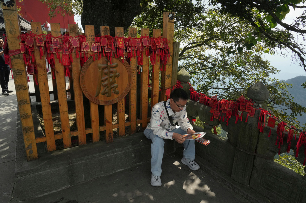 A visitor sits near wishes written on red cards near the Golden Hall in Wudang Mountains in central China's Hubei Province on Sept. 3, 2026. (AP Photo/Achmad Ibrahim)