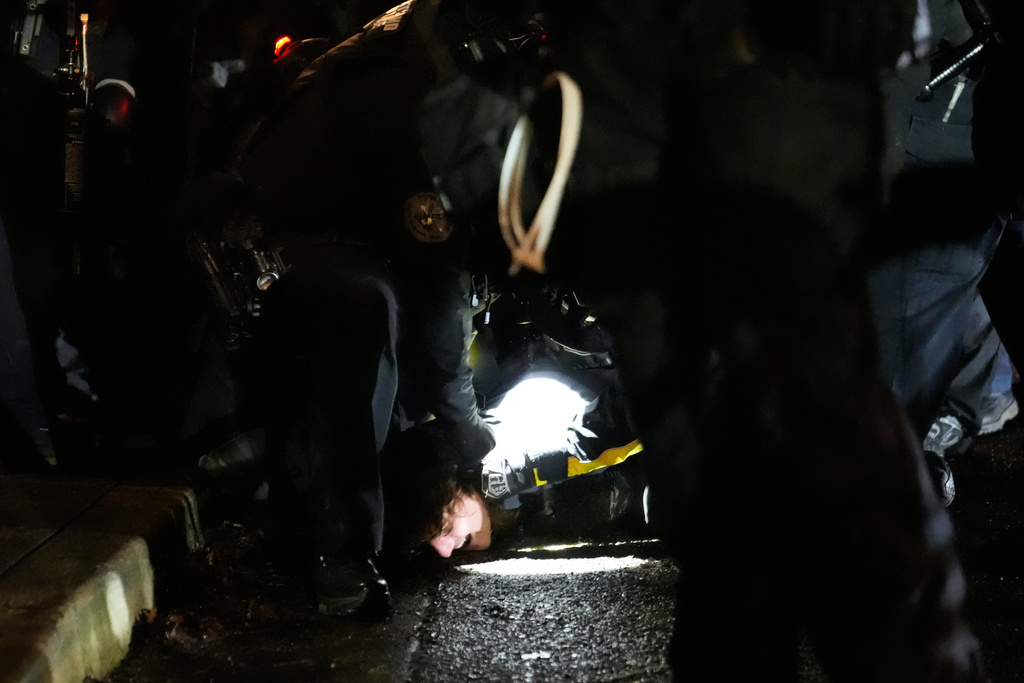 Law enforcement detain a protester outside the U.S. Immigration and Customs Enforcement facility on Thursday, Jan. 8, 2026, in Portland, Ore. (AP Photo/Jenny Kane)