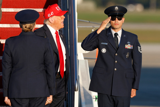 President Donald Trump, center, is greeted by Air Force 89th Air Wing Deputy Commander Melissa Dombrock, left, as he speaks to the media upon his arrival at Joint Base Andrews, Md., Sunday, Oct. 5, 2025, after returning from Norfolk, Va. (AP Photo/Luis M. Alvarez) President Donald Trump, center, is greeted by Air Force 89th Air Wing Deputy Commander Melissa Dombrock, left, as he speaks to the media upon his arrival at Joint Base Andrews, Md., Sunday, Oct. 5, 2025, after returning from Norfolk, Va. (AP Photo/Luis M. Alvarez)