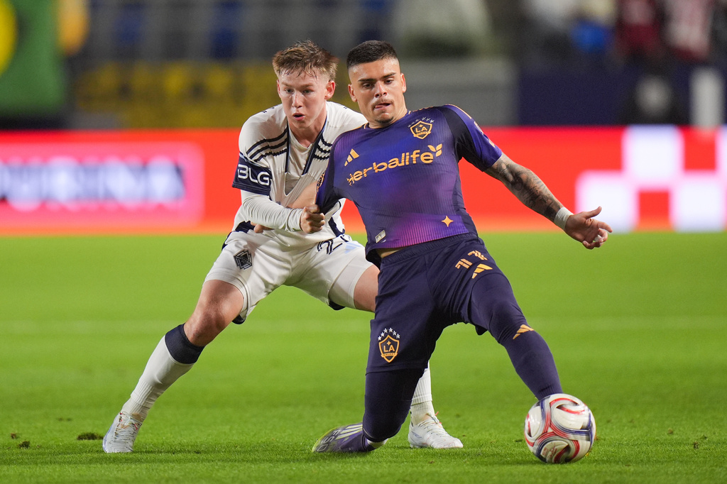 Vancouver Whitecaps defender Tate Johnson (28) grabs the jersey of Los Angeles Galaxy midfielder Gabriel Pec (11) during the first half of an MLS soccer match Saturday, May 2, 2026, in Carson, Calif. (AP Photo/Jae C. Hong)