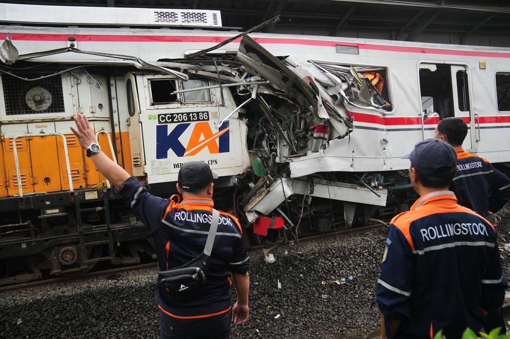 Workers examine the wreckages of trains after a collision in Bekasi, Indonesia, Tuesday, April 28, 2026. (AP Photo/Tatan Syuflana)